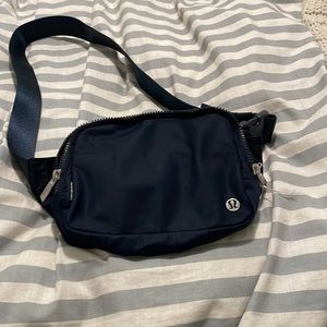 A large navy blue Lululemon belt bag
